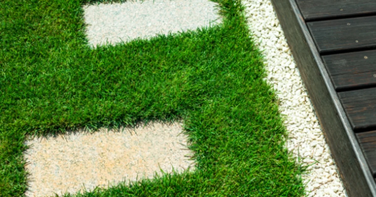 Stepping stone pathway embedded in artificial grass next to a wooden deck and white gravel edge
